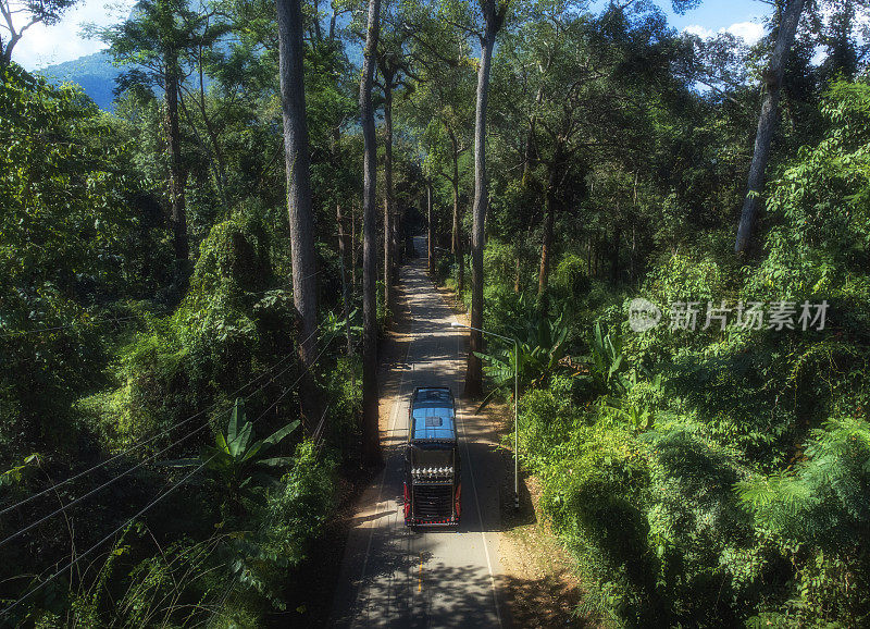 在一个明亮的日子里，在秋天的森林中有笔直的道路的Doi Luang Chiang Dao山的空中景观。